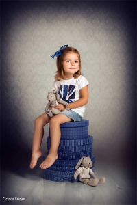 Niña posando sobre cajas en estudio fotográfico