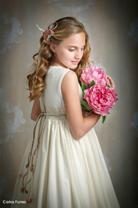 Lucia posa para las fotografías de Primera Comunión de espaldas en tres cuartos sujetando un ramo de flores rosas dejando lucir su precioso pelo dorado