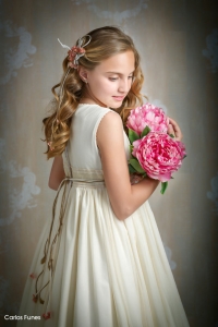 Lucia posa para las fotografías de Primera Comunión de espaldas en tres cuartos sujetando un ramo de flores rosas dejando lucir su precioso pelo dorado