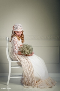 Lucia en una pose sentada sujetando un ramo de flores vestida de primera comunión firma Larrana