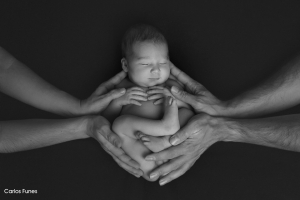 Fotografía de recién nacida entre las manos cuidadosas de sus papás. Estudio de fotografía Carlos Funes Granada.