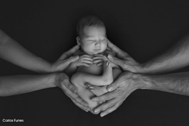 Fotografía de recién nacida entre las manos cuidadosas de sus papás. Estudio de fotografía Carlos Funes Granada.